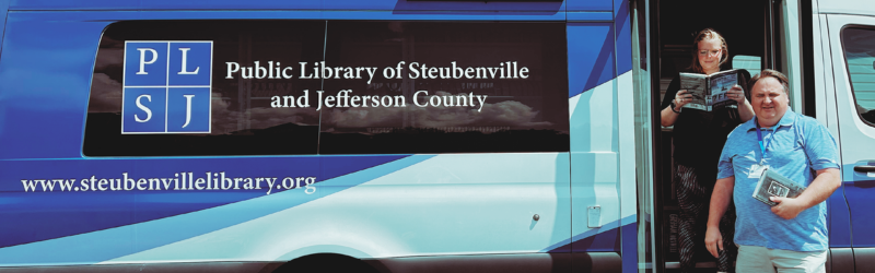 people standing in the doorway of a bookmobile holding books